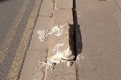 close up of a classic wide Barnet kerbstone dislodged by being driven on