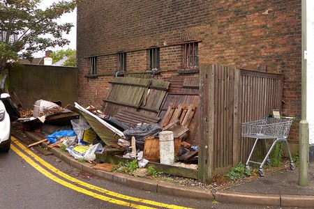 dumped fence panels and other rubbish at side of road