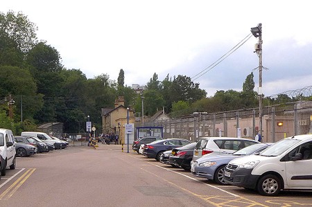 parked cars with yellow brick victorian station buildings in the distance