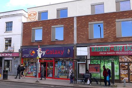shop front with a smiley face graffiti high up on the wall