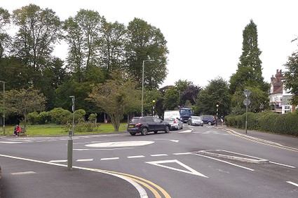 mini-roundabout in white paint with trees in the background